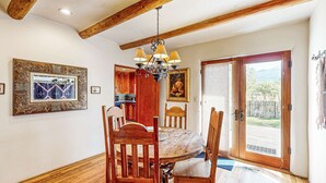 A dining area with wooden chairs, a round table, and a chandelier. - Casa Raya Taos - Mountain Views, Yard & Near Plaza (Taos)