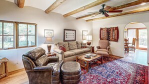 A spacious living room with a leather sofa, a wooden coffee table, and a patterned rug. - Casa Raya Taos - Mountain Views, Yard & Near Plaza (Taos)