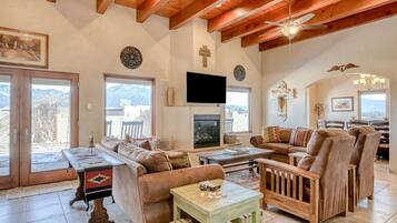 A spacious living room with a fireplace, wooden ceiling beams, and a television.