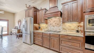 A kitchen with wooden cabinets, a stainless steel refrigerator, a tiled backsplash, and a built-in oven.
