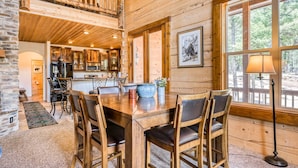 Interior de madera con comedor, cocina y ventanas amplias.
