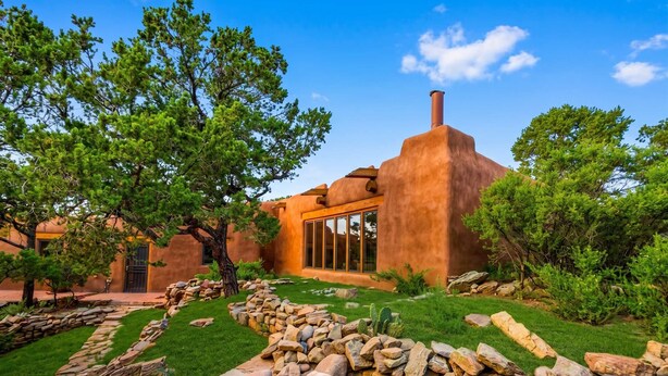 Un bâtiment rustique avec un chemin de pierre, de l’herbe verte et des arbres.