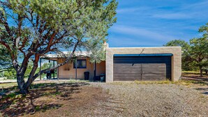 Una casa con garage, vialetto sterrato e un albero.