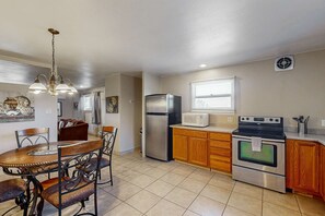 A kitchen with a dining table, chairs, a refrigerator, a microwave, and an oven.