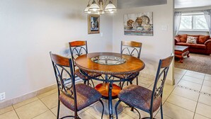 Zona pranzo con tavolo rotondo, sedie e lampadario.