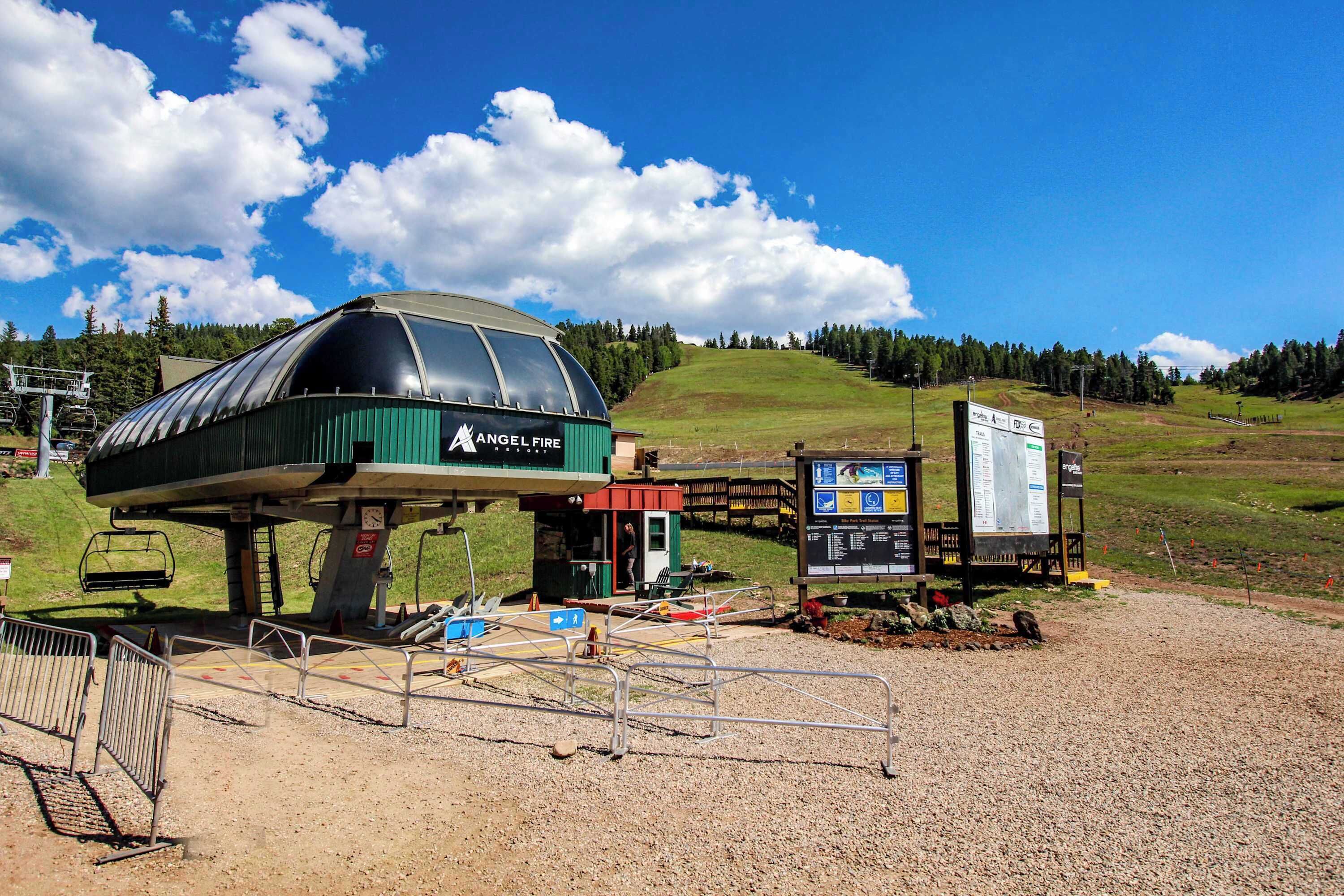 A ski lift station with a covered waiting area, a small building, and informational signs.