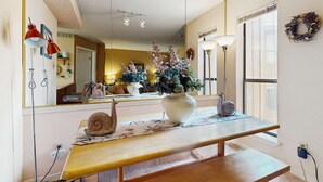 Ein Zimmer mit einem großen Spiegel, einer hölzernen Bank, einer Vase mit Blumen und einer Lampe.