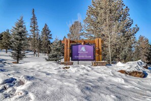 Naamplaatje voor Angel Fire Country Club, omringd door besneeuwde grond en bomen.