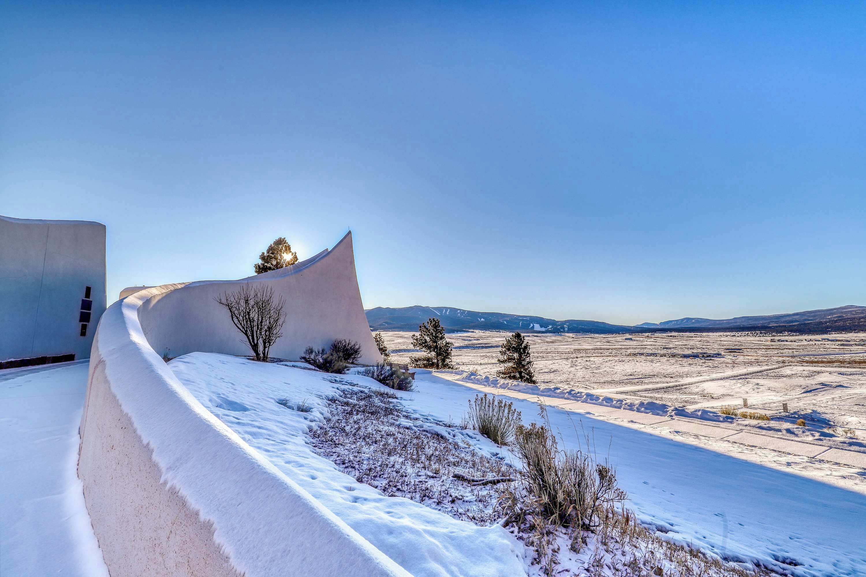 A snow-covered landscape with a unique curved building structure.