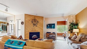 Ein Wohnzimmer mit Kamin, Sofas, einem Fernseher und einem großen Fenster.