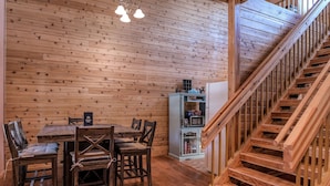 Un intérieur en bois comprenant une table et des chaises, un escalier et une petite cuisine.