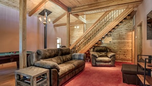 Un intérieur en bois, agrémenté d’une moquette rouge, d’une table de billard, de canapés en cuir et d’un escalier.