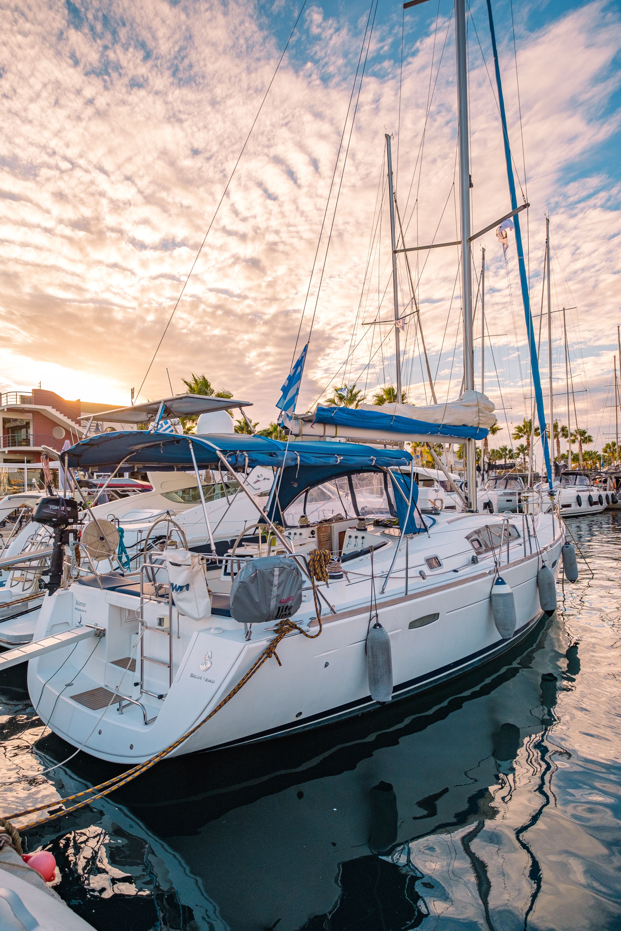 A marina with multiple sailboats docked, featuring masts, sails, and various nautical equipment.