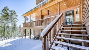 Una cabana de fusta amb un balcó, una escala i un paisatge cobert de neu.