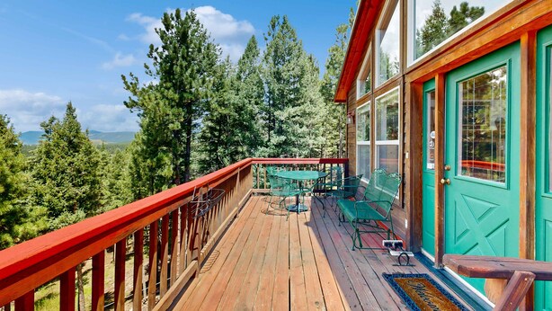 A wooden deck with a red railing, green outdoor furniture, and a turquoise door. - El Camino Real Retreat - Views, Hot Tub & Pets Ok (Angel Fire)