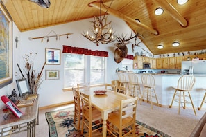 A wooden interior with a dining table, chairs, a chandelier, and a mounted deer head. - El Camino Real Retreat - Views, Hot Tub & Pets Ok (Angel Fire)