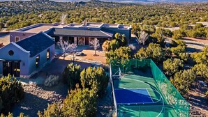 A residential property with a large house, a tennis court, and surrounding trees. - Windy Acres Retreat - Patio, Outdoor Kitchen, Gym (Santa Fe)