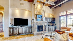 A spacious living room with a stone fireplace, a television, and leather sofas. - Windy Acres Retreat - Patio, Outdoor Kitchen, Gym (Santa Fe)