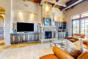 A spacious living room with a stone fireplace, a television, and leather sofas. - Windy Acres Retreat - Patio, Outdoor Kitchen, Gym (Santa Fe)