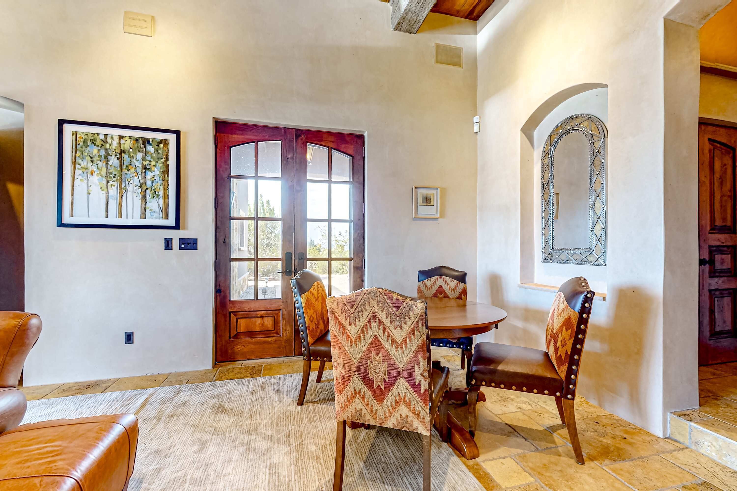 A dining area with a wooden table and chairs, a rug, and a framed picture on the wall.