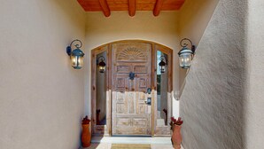 Una porta de fusta amb un finestral superior, una paret de pedra i un sostre de fusta.