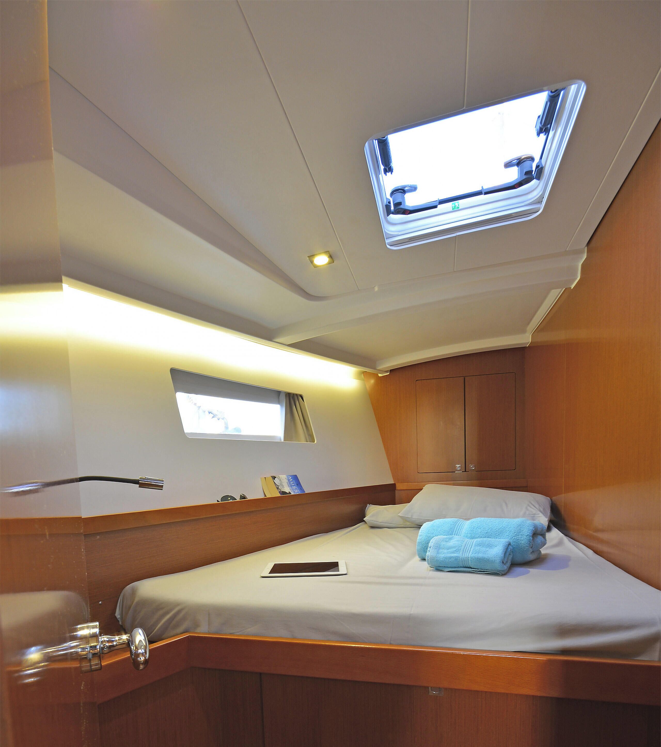 A cabin with a bed, a window, a ceiling light, and a small table.