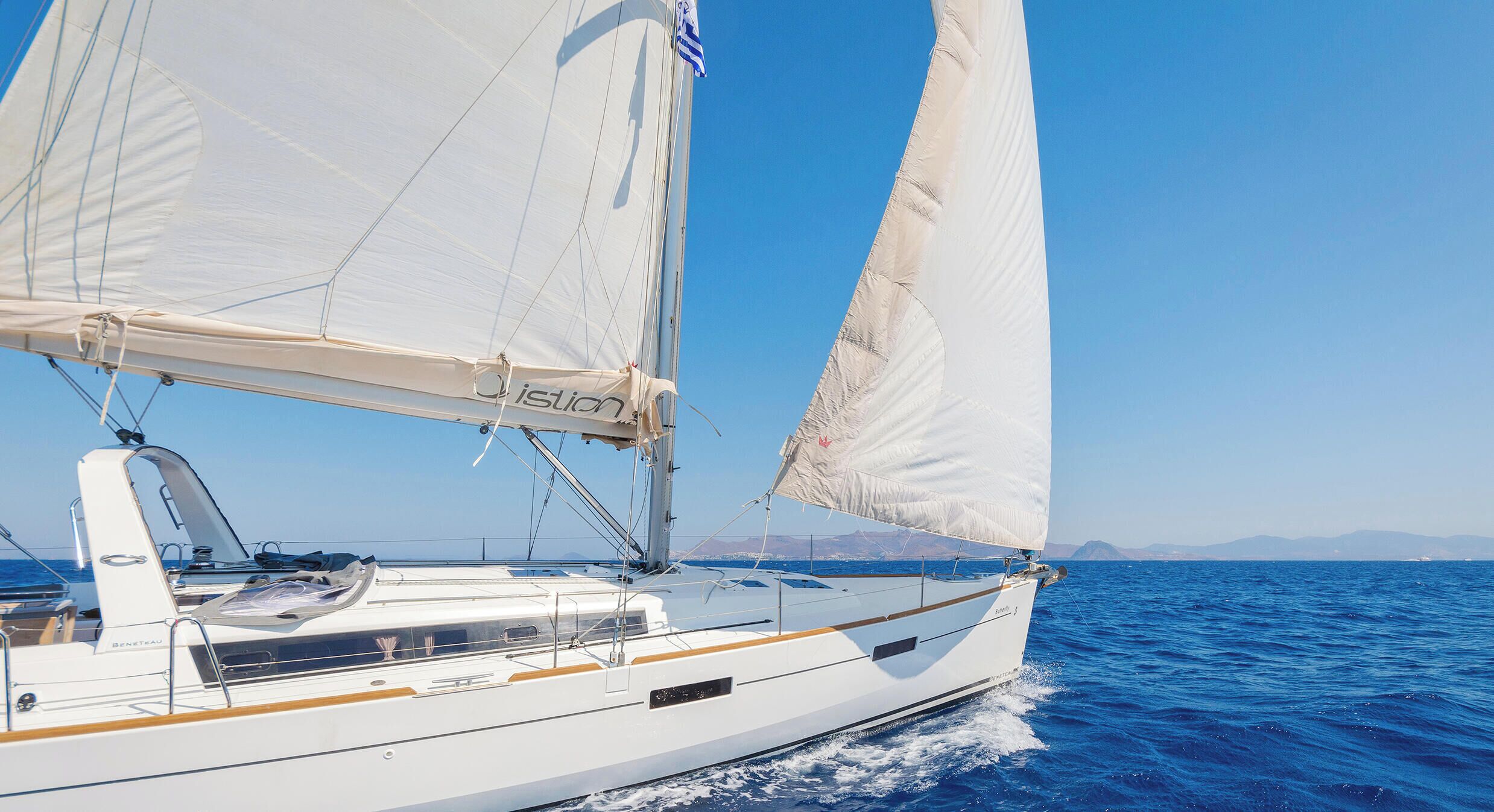 Een zeilboot met een witte romp, een hut met een raam en een vlag op de mast.