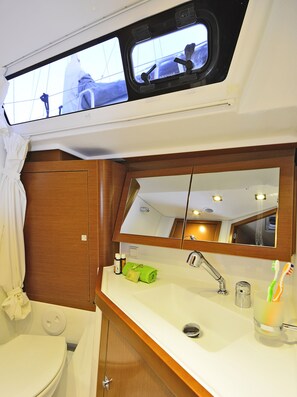 A bathroom with a toilet, sink, mirror, and a window above the sink. - Sun-Kissed Sailing Adventure in the Dodecanese Islands (Kos)