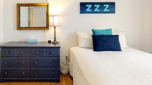 A bedroom with a bed, a dresser, a mirror, a wall clock, and a wall-mounted sign. - Kathryn Place Casita - Walk to Downtown & Railyard (Santa Fe)