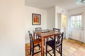 Ein Essbereich mit einem Holztisch und Stühlen, einem gerahmten abstrakten Gemälde an der Wand und einer Tür zu einem anderen Raum.