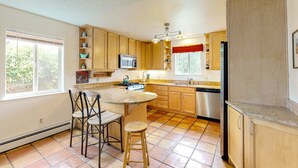 A kitchen with wooden cabinets, a gas stove, a microwave, and a dishwasher. - Kathryn Place Casita - Walk to Downtown & Railyard (Santa Fe)