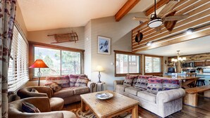 A cozy living room with two sofas, a wooden coffee table, and a dining area with a bench. - The Lift C2 - Walk to Lifts & Town, Mountain Views (Angel Fire)