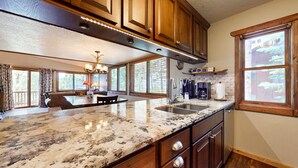 A kitchen with wooden cabinets, granite countertops, a built-in oven, and a window with a view of trees. - The Lift C2 - Walk to Lifts & Town, Mountain Views (Angel Fire)