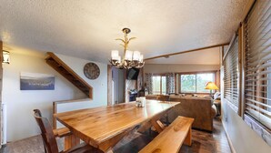 A wooden dining table with benches, a chandelier, a clock, and a staircase. - The Lift C2 - Walk to Lifts & Town, Mountain Views (Angel Fire)