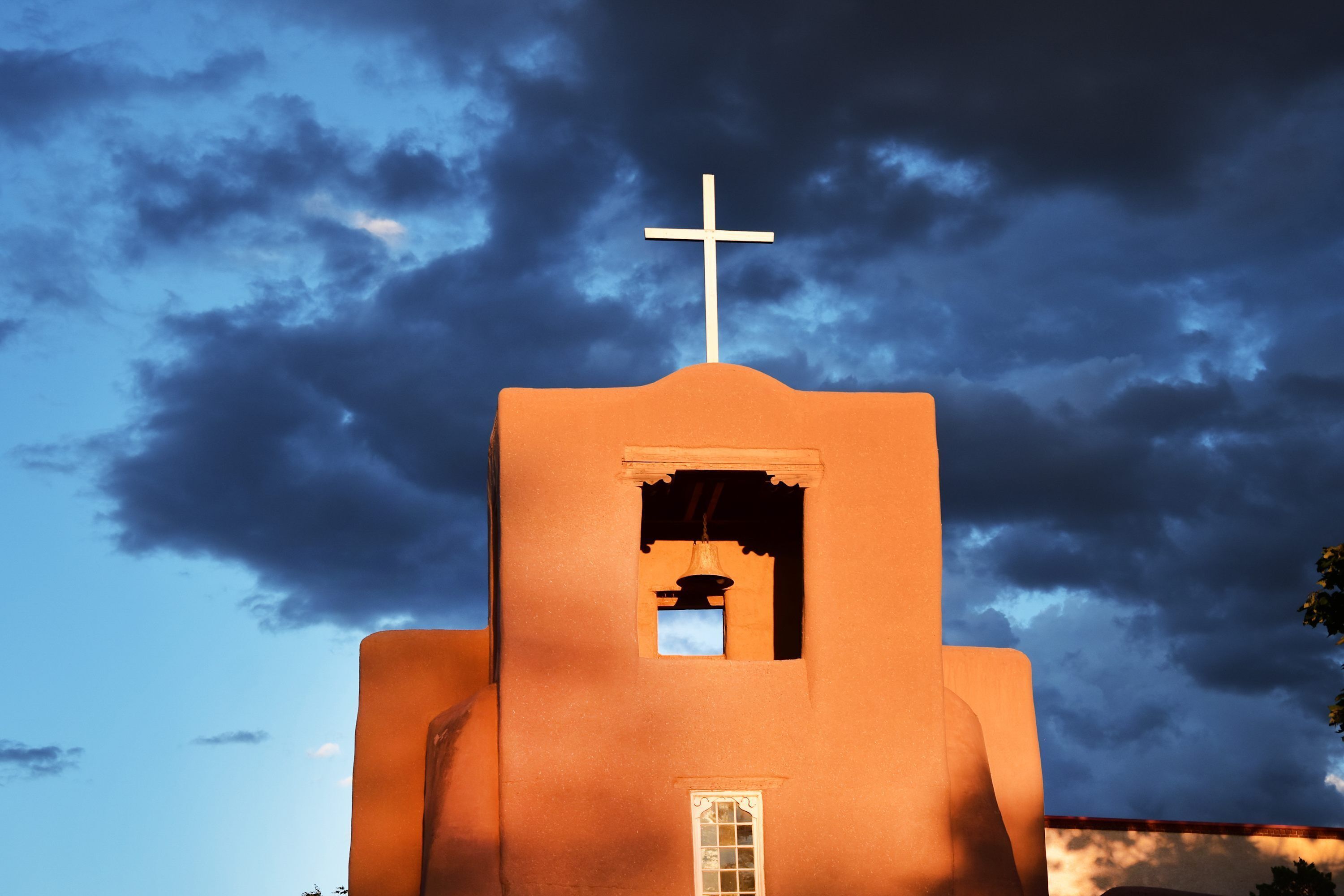 Un bâtiment surmonté d’une croix, doté d’une petite fenêtre et d’une cloche.