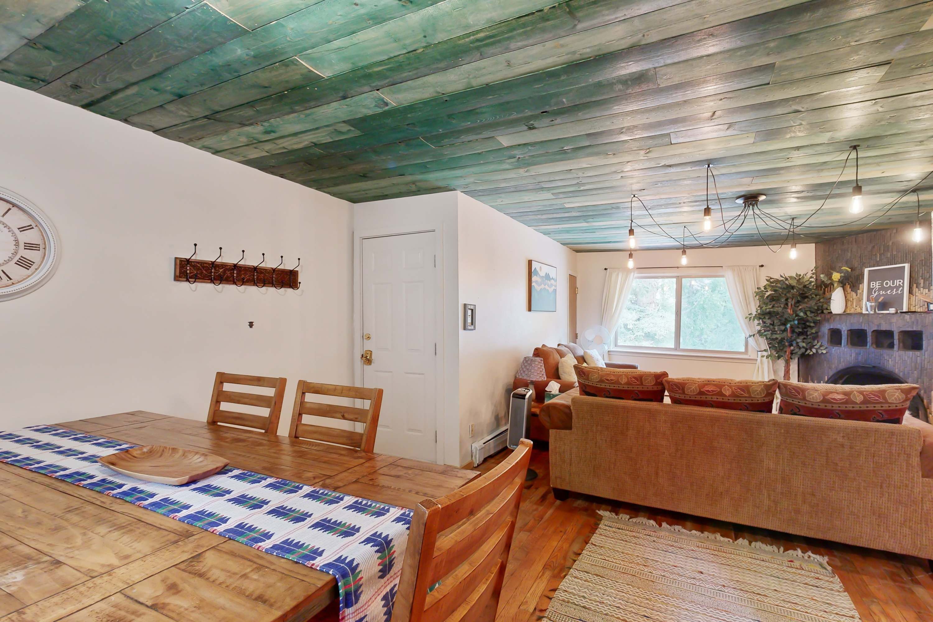 Ein Holzespeisesaal mit Stühlen, eine Couch, ein Kamin und eine Uhr an der Wand.