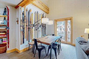 A dining area with a wooden table, black chairs, and skis mounted on the wall. - Majestic Alpine Retreat - Walk to Lifts & Town (Taos Ski Valley)