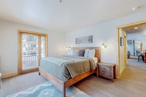 A bedroom with a bed, bedside tables, a painting, and a view of a staircase. - Majestic Alpine Retreat - Walk to Lifts & Town (Taos Ski Valley)