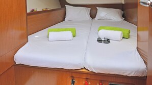 Ein kleines Kabinenzimmer mit zwei Betten, jeweils mit Kissen und Handtuch.