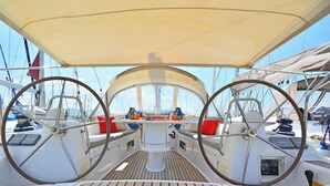 Ein Bootsdeck mit Steuerwelsen, einem zentralen Tisch und Sitzgelegenheiten mit Kissen.