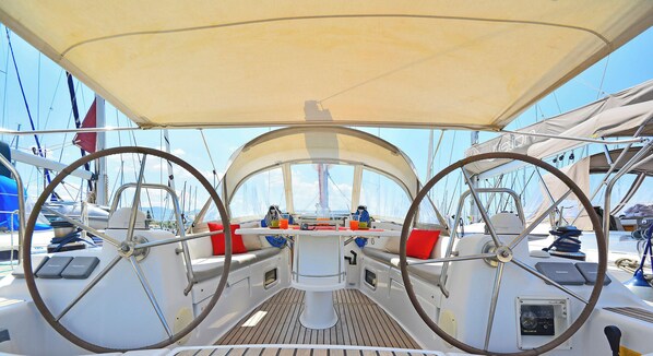 Un pont de bateau équipé de roues de direction, d’une table centrale et de sièges avec des coussins.
