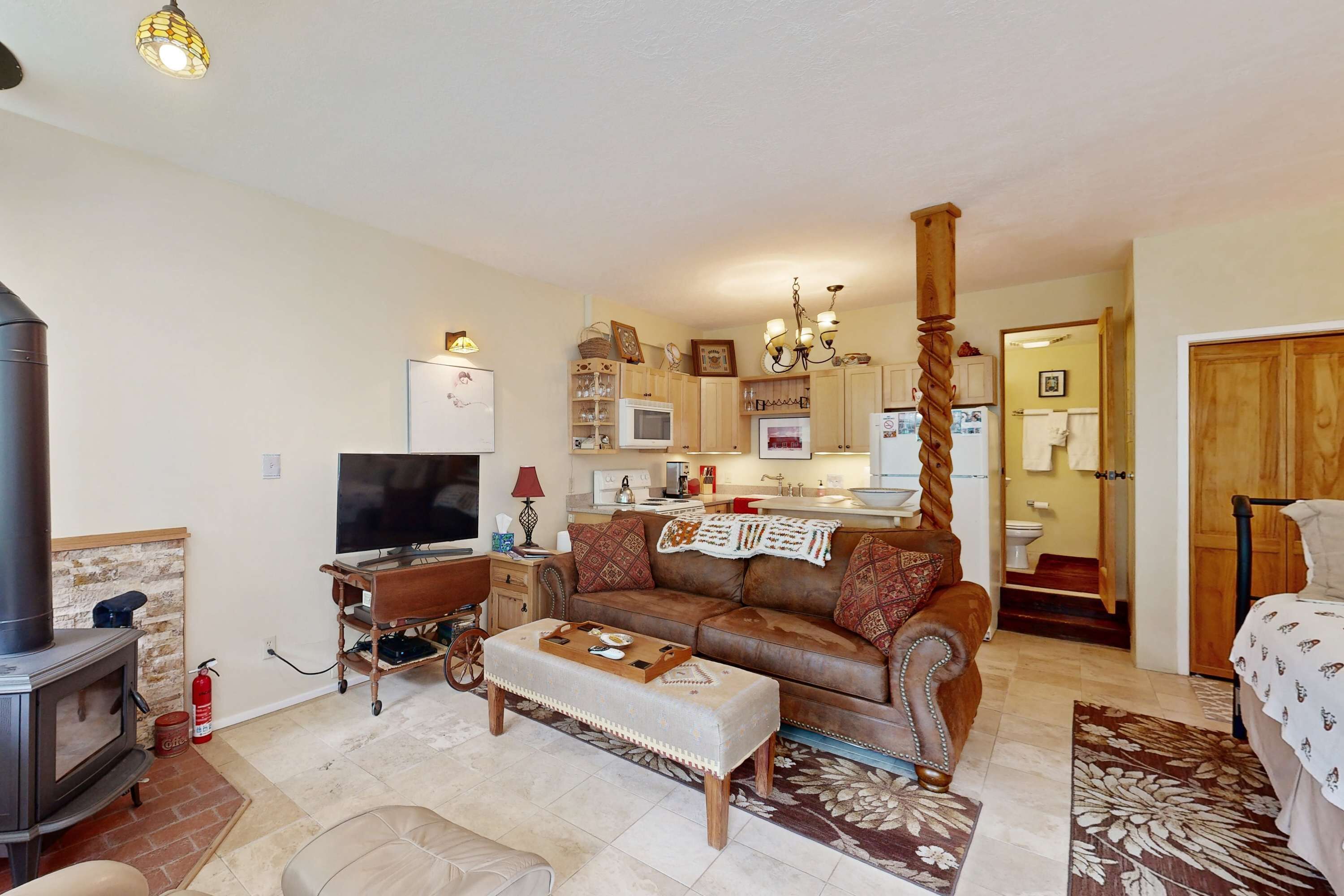 Ein gemütliches Wohnzimmer mit Kamin, Sofa, Hocker und Fernseher.