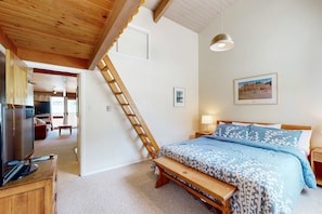 Ein Schlafzimmer mit einem Bett, einer Holzleiter, einem Fernseher und einer Bank.