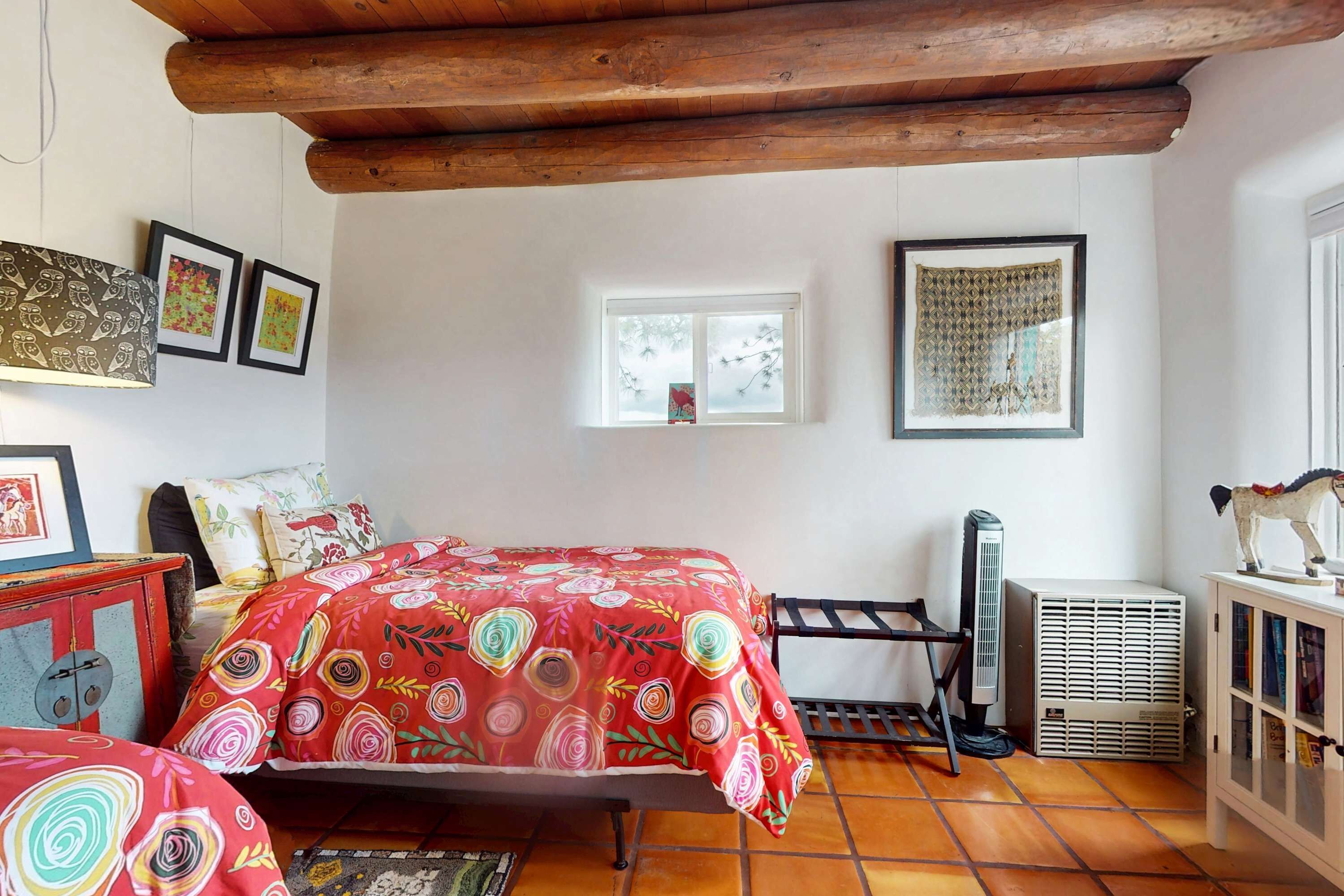 A room with a bed, a radiator, a window, and a cabinet with books.