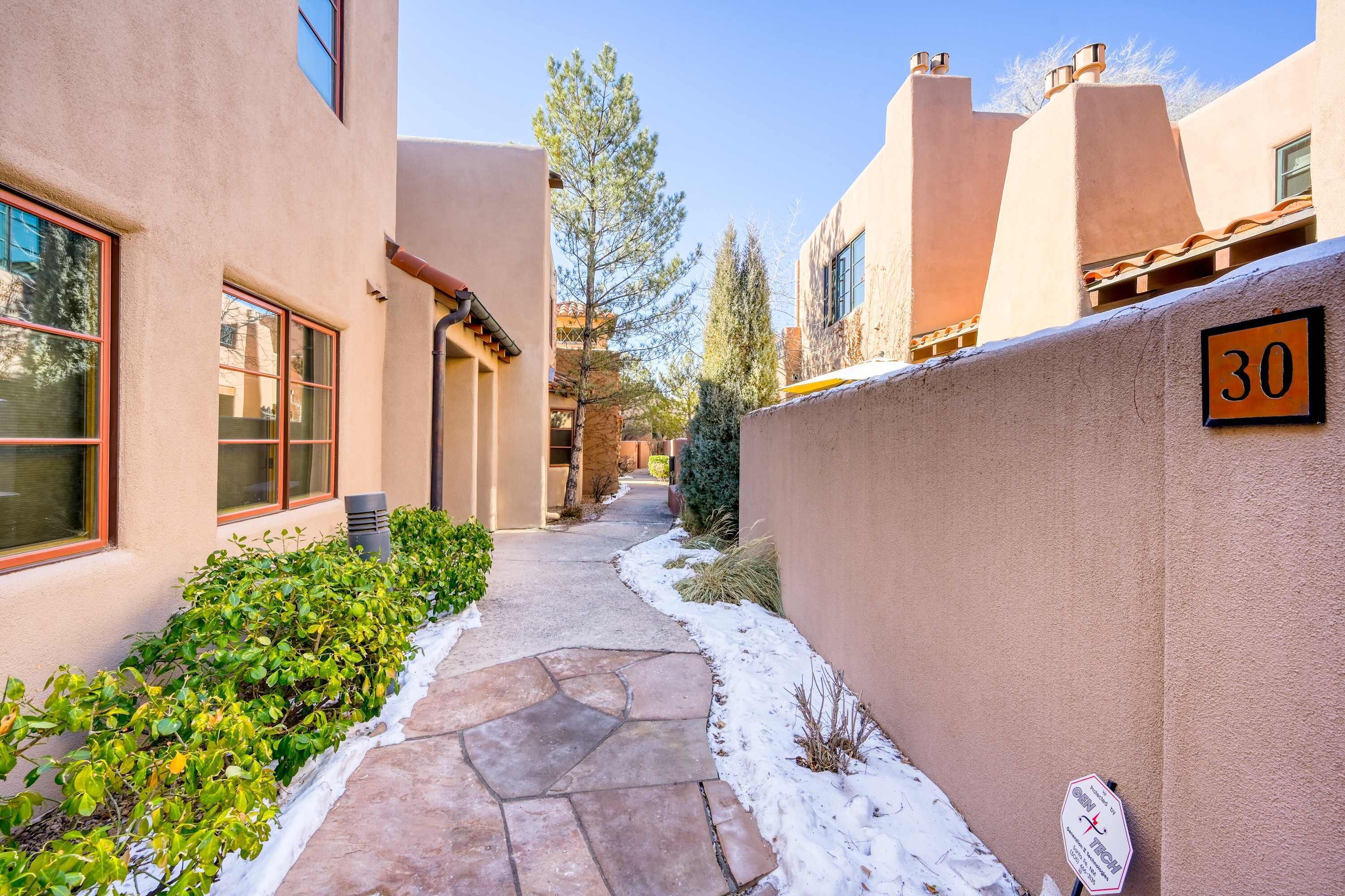 A narrow pathway flanked by buildings with stucco walls and a number sign indicating unit 30.