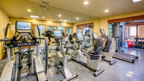 Ein Fitnessstudio mit verschiedenen Trainingsgeräten, darunter Laufbänder, Ergometer und Kraftgeräte.