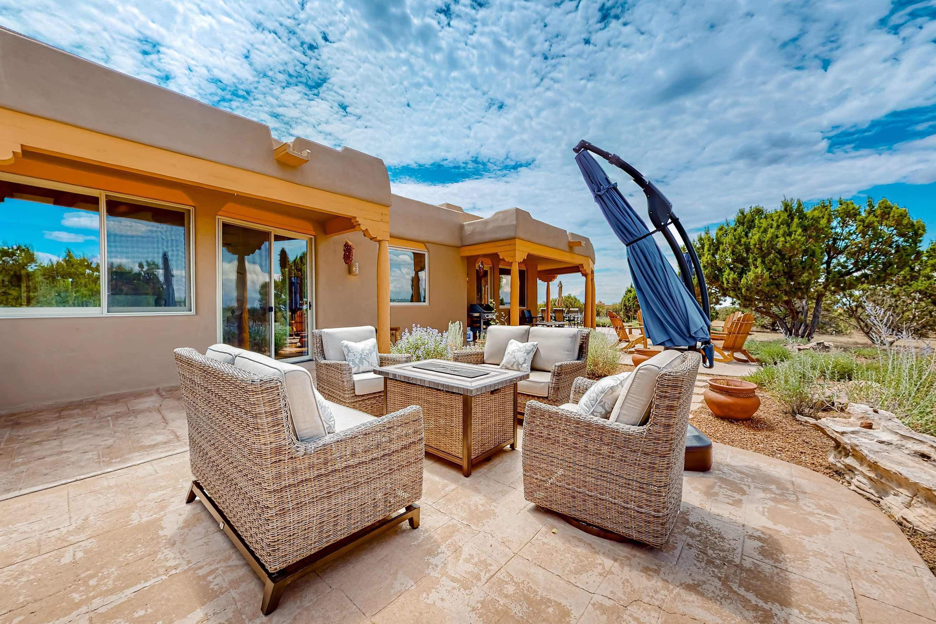 Un patio al aire libre con muebles de mimbre, una mesa y un paraguas azul.