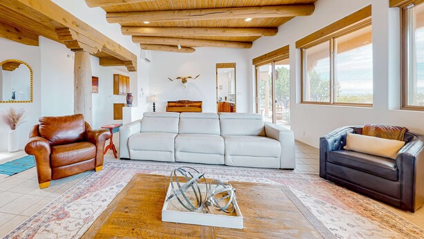 A spacious living room with a high wooden ceiling, a white sofa, leather armchairs, and a coffee table with metal sculptures. - Dos Vistas - Firepit, Hot Tub, Mountain Views (Santa Fe)