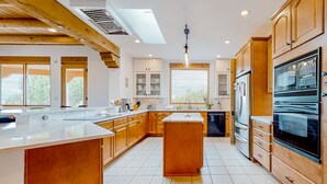 A modern kitchen with wooden cabinets, a large island, and built-in appliances. - Dos Vistas - Firepit, Hot Tub, Mountain Views (Santa Fe)
