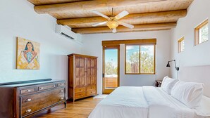 A bedroom with a wooden ceiling, a ceiling fan, a large bed, a wooden dresser, and a painting on the wall. - Dos Vistas - Firepit, Hot Tub, Mountain Views (Santa Fe)